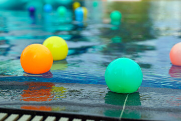 Colorful plastic balls move up and down in the same place on the surface of the water as surface waves, which are transverse waves, pass by.