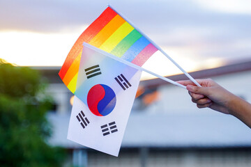 Hand holding rainbow flag and Korean flag which are decorated in homes to show the pride and identity of LGBT people. Soft and selective focus.