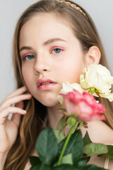 Little pretty girl in pink holds the bouquet of roses.