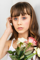 Little pretty girl in pink holds the bouquet of roses.