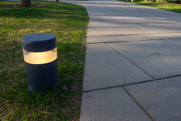 Modern pathway lighting enhances safety and aesthetic value in a park setting during late afternoon hours, showcasing thoughtful landscape design and infrastructure elements
