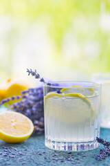 Lemonade with lemons and lavender on stone table over nature background