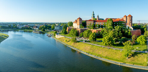 Krakow, Poland. Wide aerial panorama with Polish state owned royal Wawel castle and Gothic cathedral. Vistula river, parks, boulevards, promenades, walking and biking people. Spring, sunset light