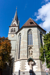 Fototapeta premium A striking low-angle view of the historic St. Stephen's Church (Stephanskirche) in Konstanz (Constance), standing tall against a bright blue sky with scattered clouds
