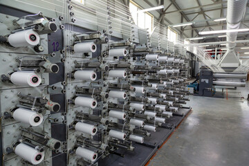 Factory equipment in perspective. Rows with coils of polypropylene threads for weaving cloth. Automatic machine. Nobody.