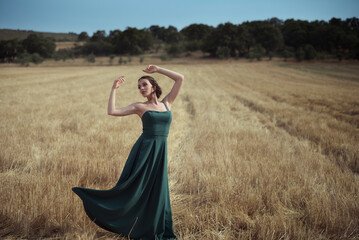 Woman in green dress dancing gracefully in golden wheat field