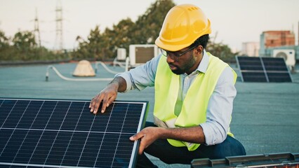 African American young happy man smiling confidently, demonstrating solar panel functionality, promoting sustainability, showcasing renewable energy solutions, ensuring efficient installations. © VAKSMANV