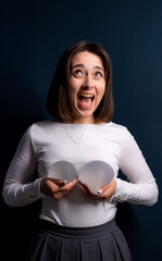 Woman playfully holding silicone breasts. A woman joyfully holds silicone breast forms while...