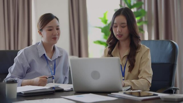 Female mentor instructing new employee on workplace process and career success strategy at business office