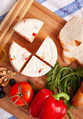 Variety of home made cheese and paprica and herbs, olive oil, olives and bread on a wooden board. Brined curd white cheese with vegetables on the table