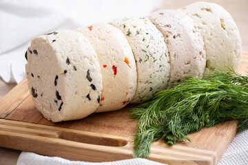 Directly above on several varieties of homemade cheese with different fillings with paprika, dill, olives, walnuts and cookies on a wooden board with fresh dill.