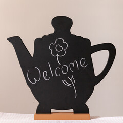 A real blackboard in the form of a teapot with a drawing on a stand