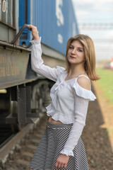 Portrait of a young beautiful blonde girl on the railway.