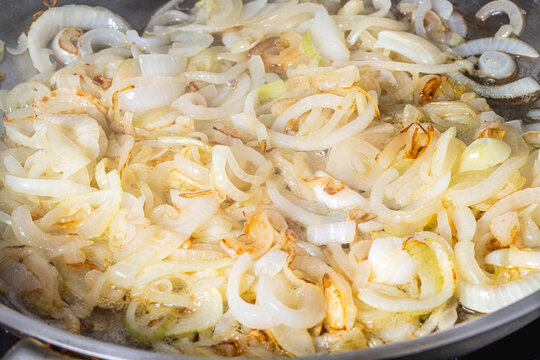 The onion is fried in a pan. The process of cooking onion soup. Caramelization of onions