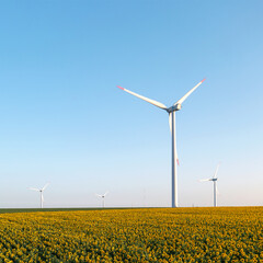 Large wind turbines with blades in field aerial view bright orange sunset blue sky wind park slow motion drone turn. Silhouettes windmills, large orange sun disc summer lens flare. Alternative energy