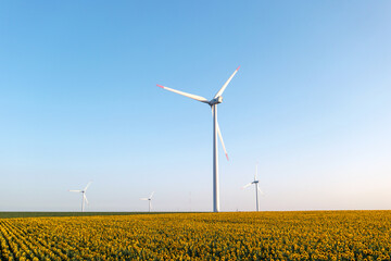 Alternative energy wind turbines with blades in field aerial view bright orange sunset blue sky wind park slow motion drone turn. Silhouettes windmills summer. Nature