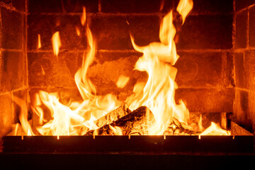Brick fireplace lit with wood fire, strong bright flames, creating interior comfort, rural cozy evening, winter heat, peaceful countryside atmosphere