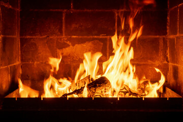 Burning fireplace logs with high flames inside brick hearth, cozy interior warmth, traditional home heating, rustic ambiance, romantic cabin atmosphere, winter season comfort, firewood crackling sound