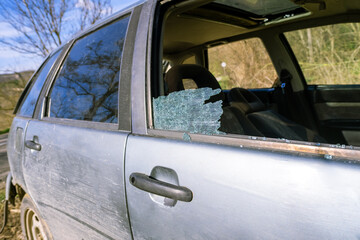 Broken car glass detail, view through destroyed side window, showing inside seats, aftermath of robbery, property damage issue, road crime alert