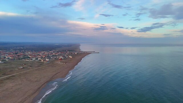 Aerial video of a coastal town meeting the sea at dawn.An aerial shot of a coastal town nestled beside a sandy beach, meeting the calm, turquoise-toned sea. Sakarya Adapazari Turkiye Karasu holiday 