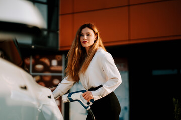 Woman charging electric car at a modern charging station during daylight