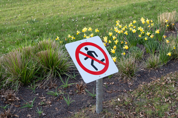 The sign in the park prohibits running on lawns to preserve green spaces. It reminds visitors of...