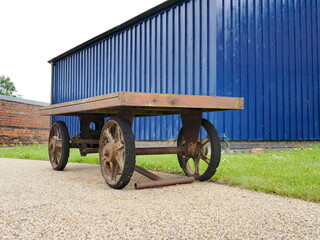 Vintage metal cart with wooden surface in outdoor setting.