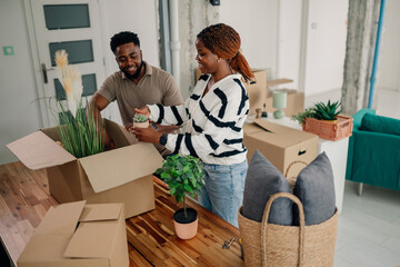 Happy couple unpacking plants in new home