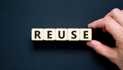 Reuse symbol. Concept word Reuse on beautiful wooden blocks. Beautiful black table black background. Businessman hand. Business lifestyle ecological reuse concept. Copy space.