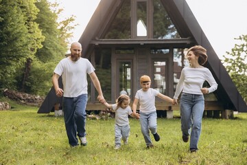 Happy family running in the garden of their modern a frame house