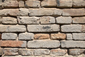 Close-up full-frame old brick wall with weathered, rustic texture and visible mortar. Sand-colored bricks, rough surface, background or construction detail wallpaper. Horizontal bricks gritty surface.