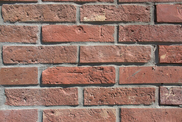 Obraz premium Close-up full-frame red brick wall, horizontal bricks with rough texture and cement joints. Rustic, weathered masonry background. Architecture, construction, and design project. Urban background. 
