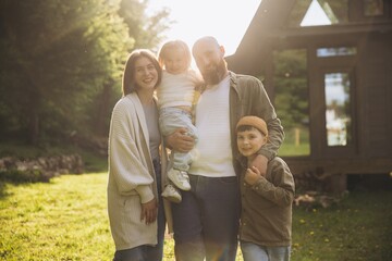 Happy family posing in front of their cabin in the woods