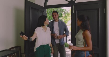 Diverse real estate agents welcoming clients, opening black front doors and touring dining area - Powered by Adobe