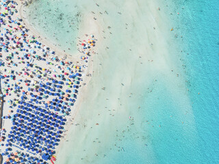 Summer vacation and rest. Beach, people and umbrellas. Top view from drone at the beach and azure sea. View on the coast from drone. Background, wallpaper, postcards.