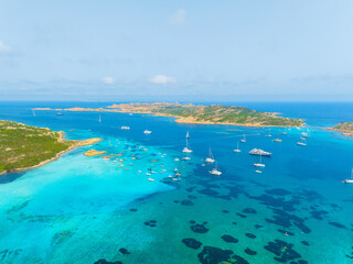 Island in the middle of the sea. Drone view of a yachts, boats and island. Vacationing people. North-Eastern Sardinia, Maddalena Archipelago. Vacation and holidays. Background, wallpaper, postcard.