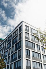 Obraz premium Modern office building with black and white facade and blue windows, on a sunny day