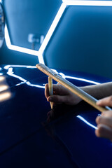 Precision tapping tool refines car surface during paintless dent repair under bright hexagonal LED...