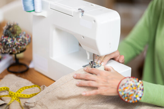 Close up of woman hands and sewing machine - process of making clothes