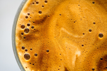 Coffee cup from above, Espresso foam texture, creamy coffee, rich, freshly brewed cup of hot latte. Top view of cappuccino milk foam closeup. Creamy coffee macro shot, on a grey table, top view. 