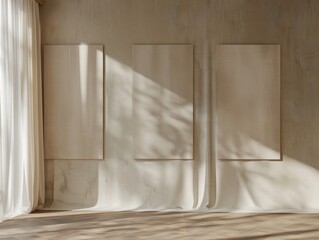 A room with three white framed pictures on the wall. The room is empty and has a lot of natural light coming in through the windows
