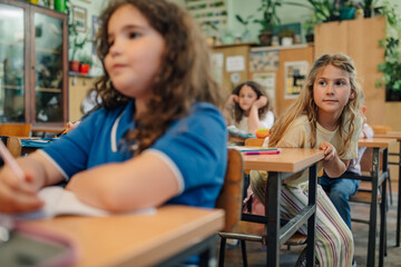 Curious elementary school student looking around classroom during lesson