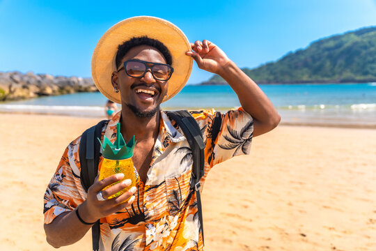 Happy tourist holding pineapple cocktail on tropical beach