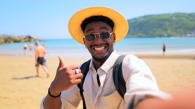Carefree black traveler wearing straw hat and backpack capturing beach selfies with vibrant ocean backdrop, radiating joy and wanderlust during sunny vacation moment