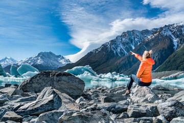 Lone tourist admiring the mountain  and glacial lake and iceberg scenery in the Tasman valley - obrazy, fototapety, plakaty