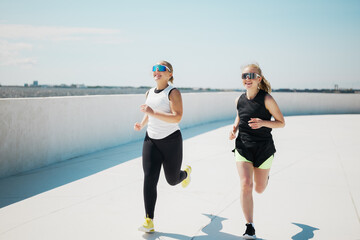 Joyful runners enjoying a sunny day on a rooftop track while staying active and fit with friends