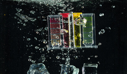 PH acid level test kit on quality water on screen. PH acid level tester kit tools fall under water splashing splattering with air bubble over black background isolated