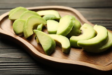 Cut ripe green avocado on wooden table, closeup