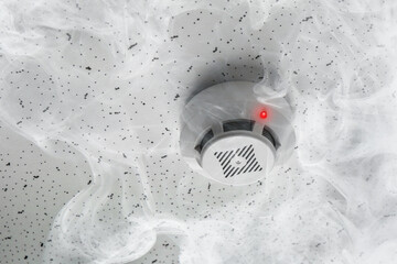 Fire alarm system. Detector on ceiling triggered by smoke