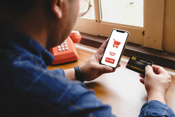 Person holding smartphone with shopping cart icon and buy now button while making online payment...